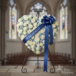 Cuore funebre di rose bianche su cavalletto con nastro blu, consegna floreale funebre a Milano – Fiori Express
