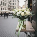 Bouquet elegante con rose bianche, lisianthus avorio ed eucalipto per compleanno uomo, davanti al chiosco Fiori Express Milano.