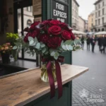 Bouquet maschile con rose bordeaux, garofani scuri ed eucalipto in vaso, realizzato da Fiori Express Milano.